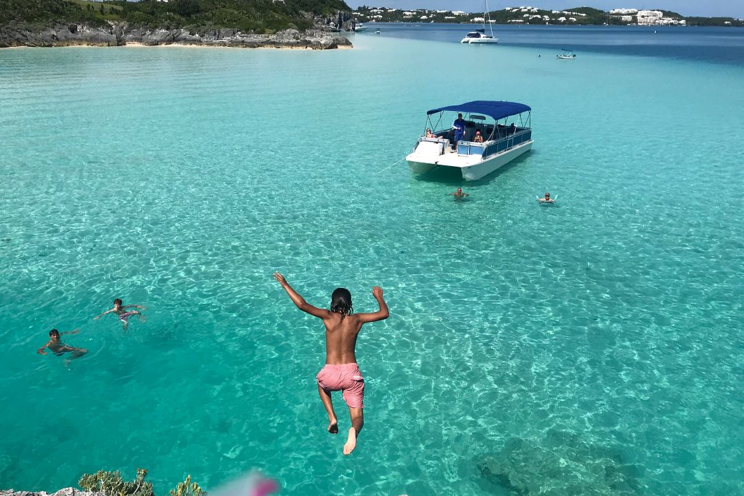 guests jumping into water with castaway boat in background